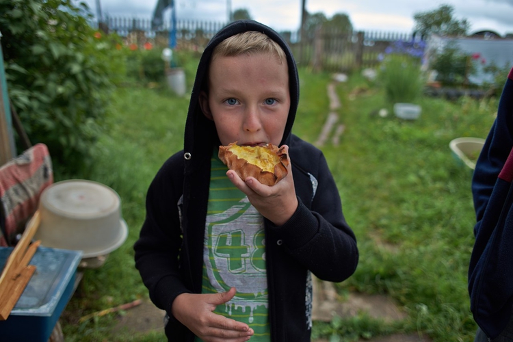 Мальчик ест традиционное финно-угорское блюдо калитки
